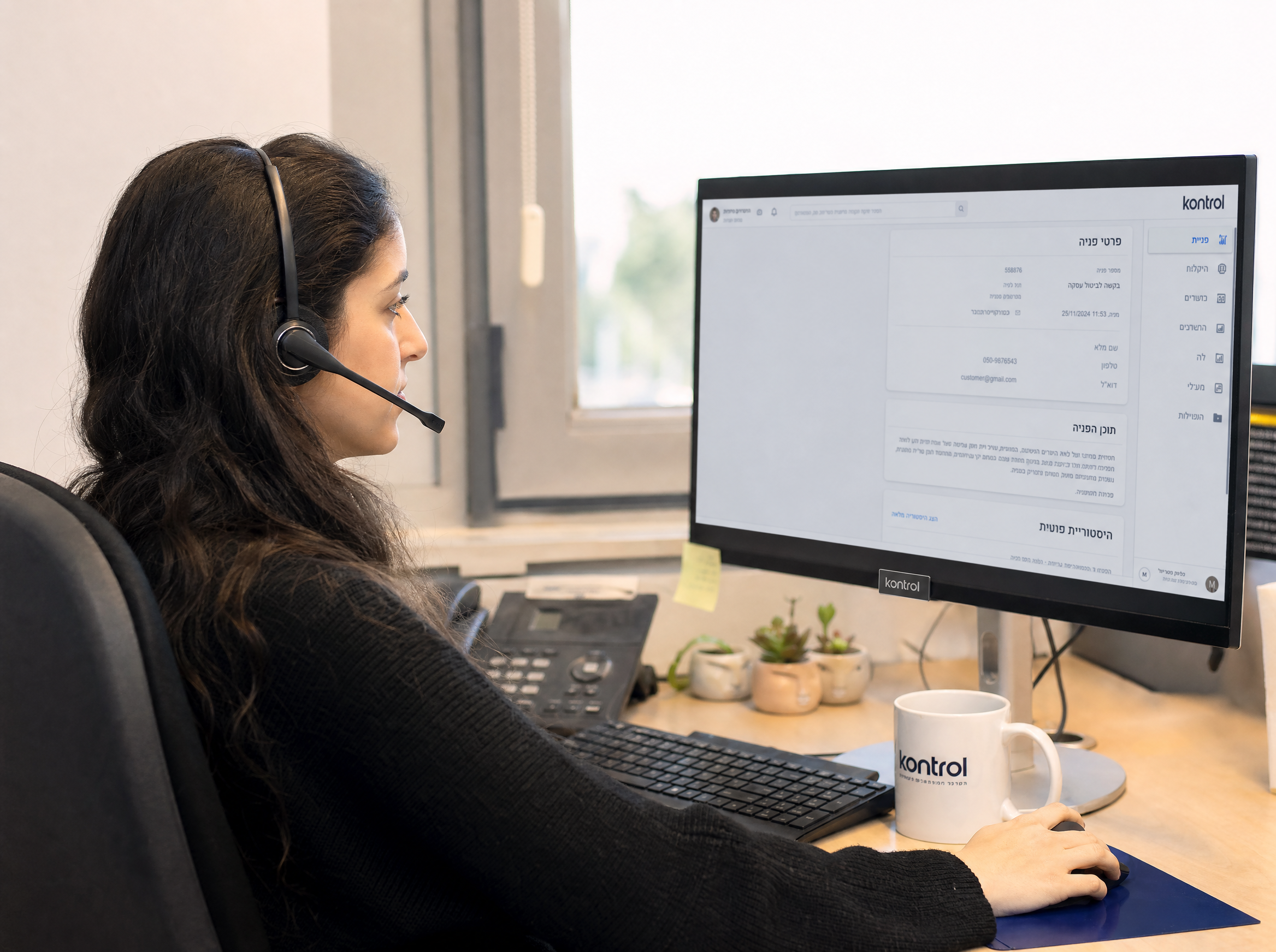 Photo of a Kontrol support operator at a desk in the Ashdod office — friendly, warm light, headset on, computer with Hebrew CRM visible. Anti-stock, real-feeling. Could also be a hands-only shot writing on a paper ticket pad with phone alongside. Real, human.