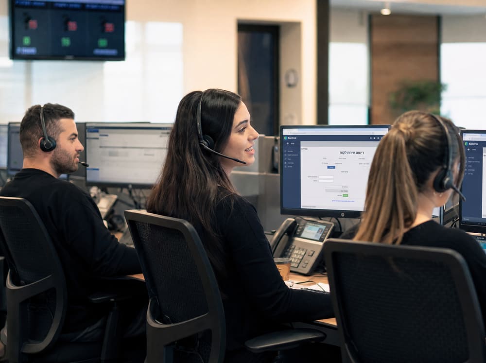 Kontrol support team in Ashdod office — 2-3 people on headsets at clean modern desks, warm light, working real customer service. Hebrew screens visible. Conveys hours-not-days response feel.