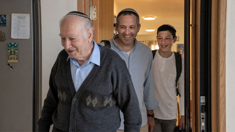 שלושה דורות של משפחה ישראלית בכניסה לדלת רב בריח — סב, אב ובן באור פנים חמים