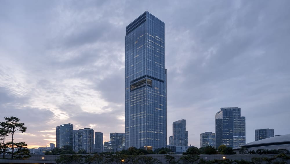 Samsung HQ Seocho Tower in Seoul — wide architectural shot, dusk grey-blue tone, conveying conglomerate scale. Subdued, respectful, no slander.